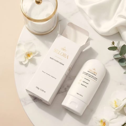 Tuýp và hộp Selora Body Filter Cream chụp flatlay trên nền cẩm thạch với hoa trắng